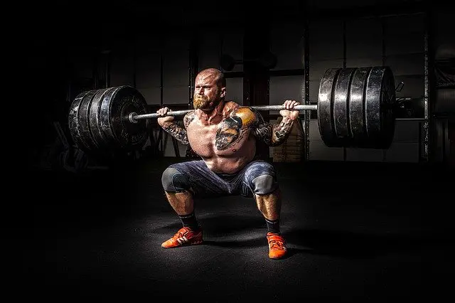 Image of a man squatting with bumper plates.