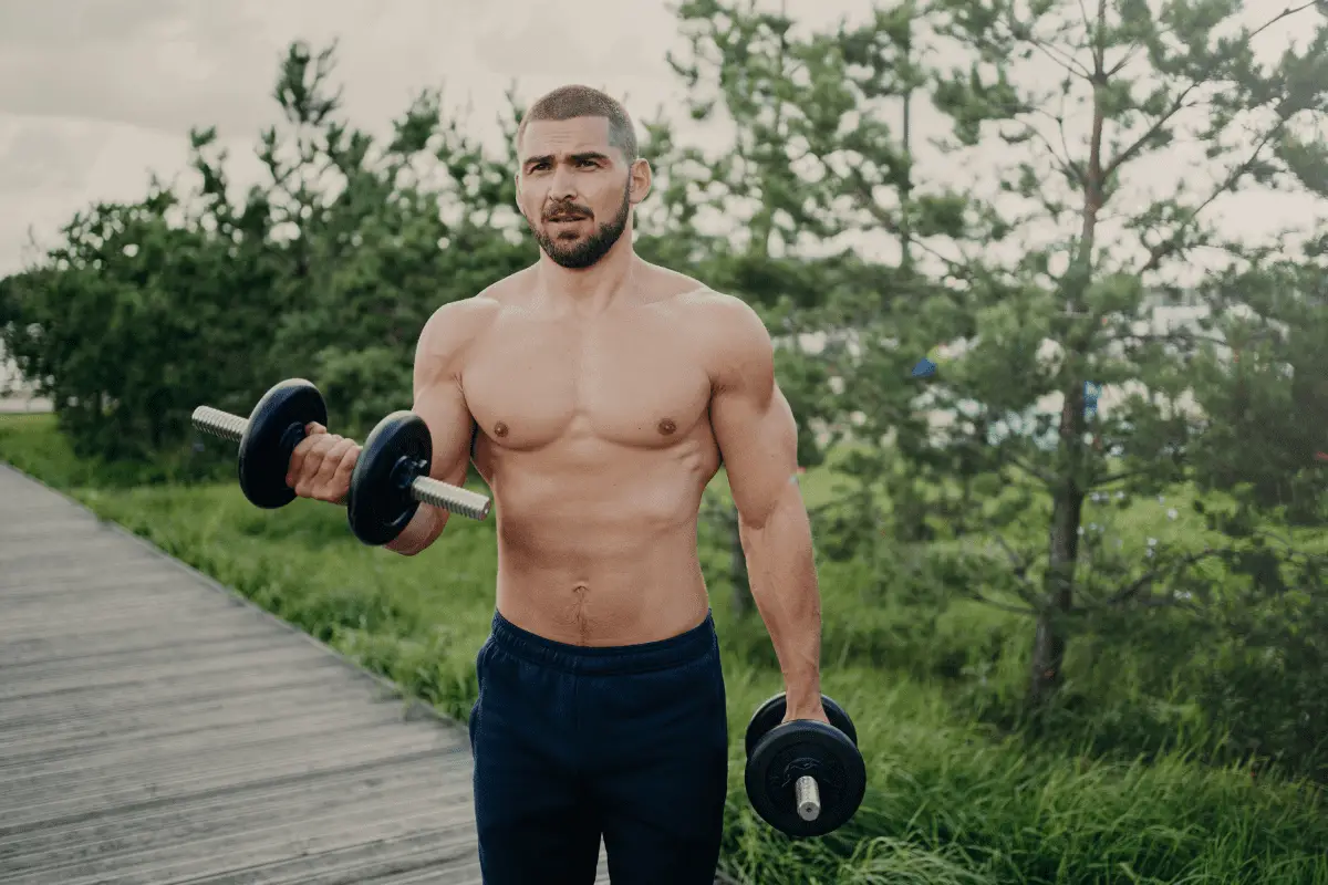 Image of a man using dumbbells outdoor