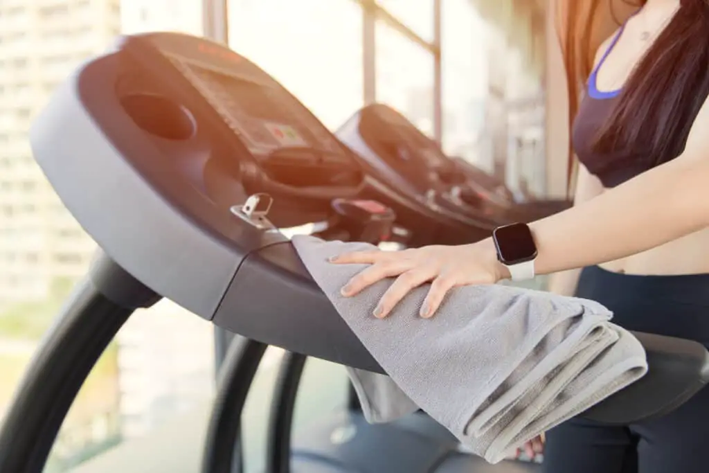 Image of a woman wiping sweat off a gym machine.
