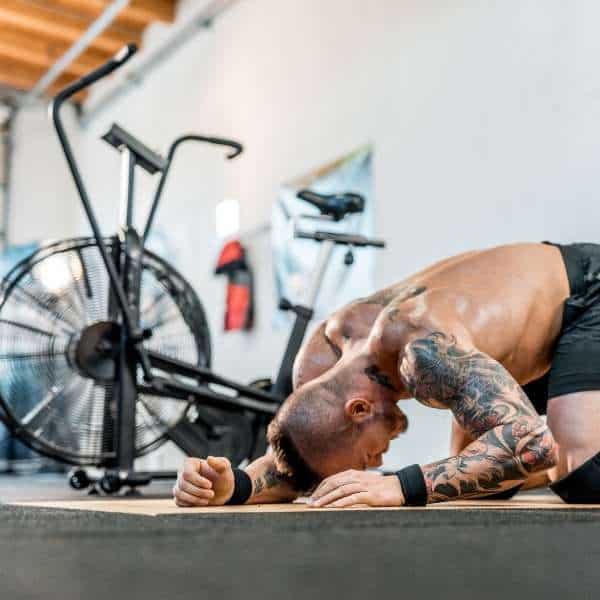 Image of a man tired in front of an Assault bike. 