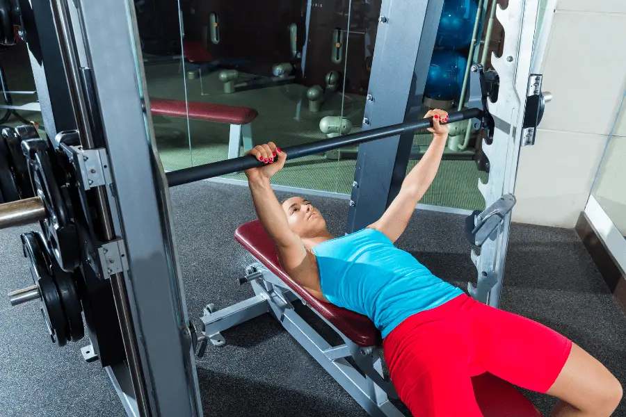 Person bench pressing in a smith machine.